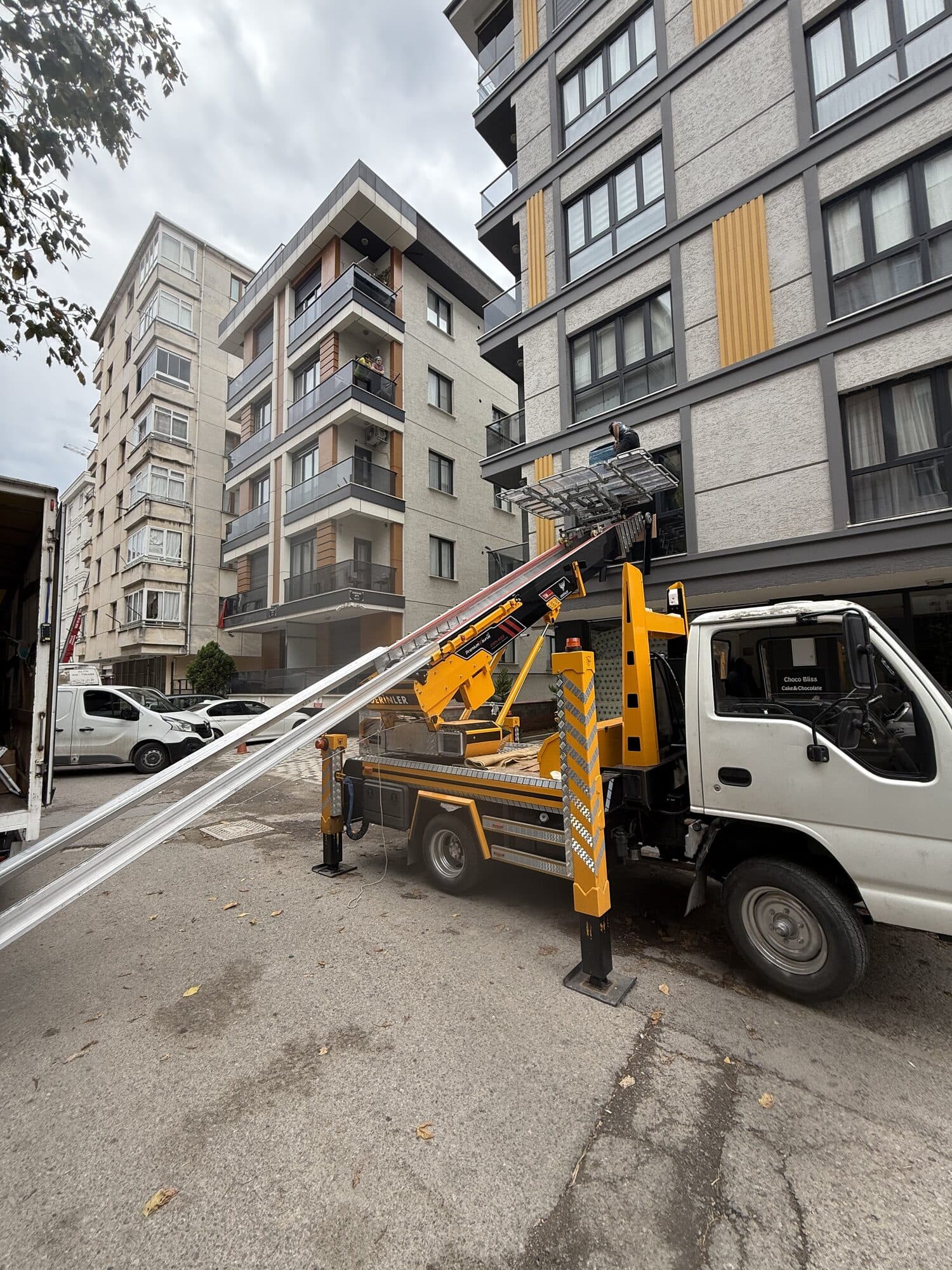 Bina önünde eşya asansörü kurulumu yapan asansörlü nakliyat aracı